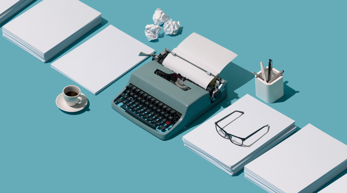 : 7 dicas de Copywriting para você. Na imagem uma máquina de escrever, alguns blocos de papel , óculos e lápis