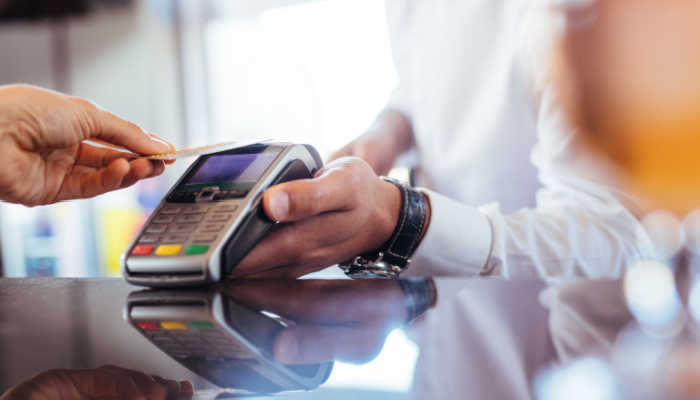 Transações financeiras mais seguras: consumidor pagando com aproximação maquininha de cartão de crédito
